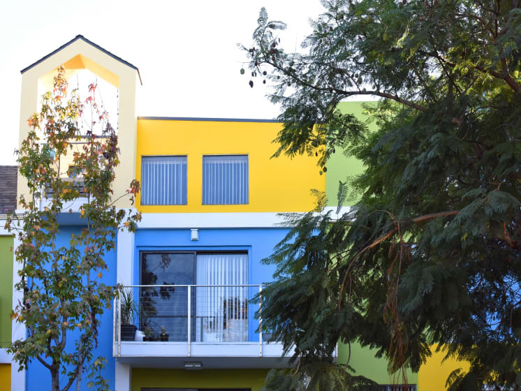Blue/Yellow Apartment Exterior with View of Private Patio, Trees